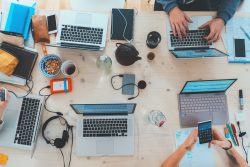 Desk with computers, cameras, external harddrive, laptops, electronic devices